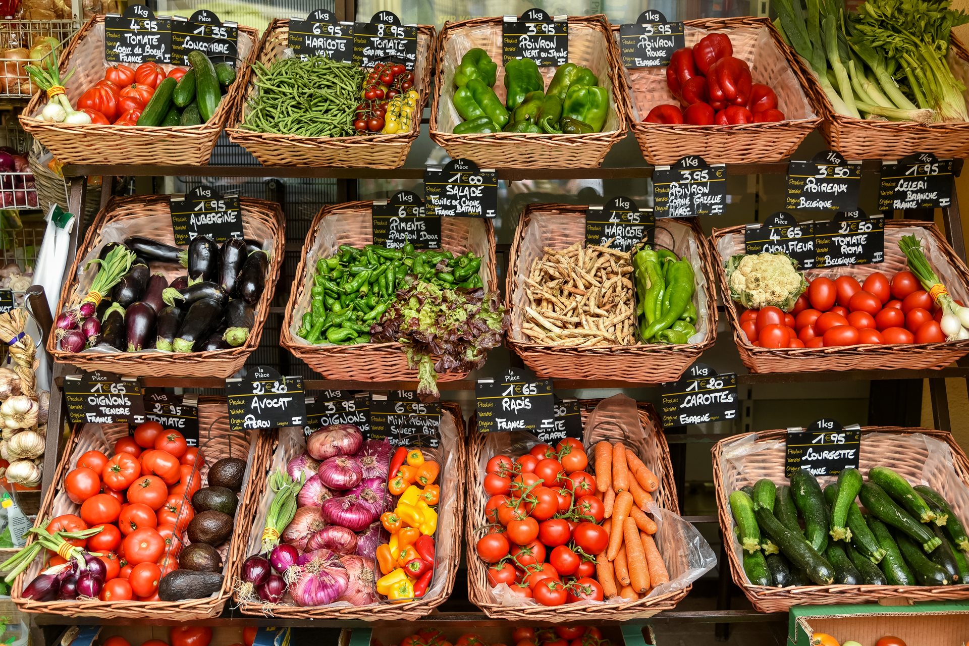 Körbe mit frischem Gemüse und Preistafeln in einem Lebensmittelladen